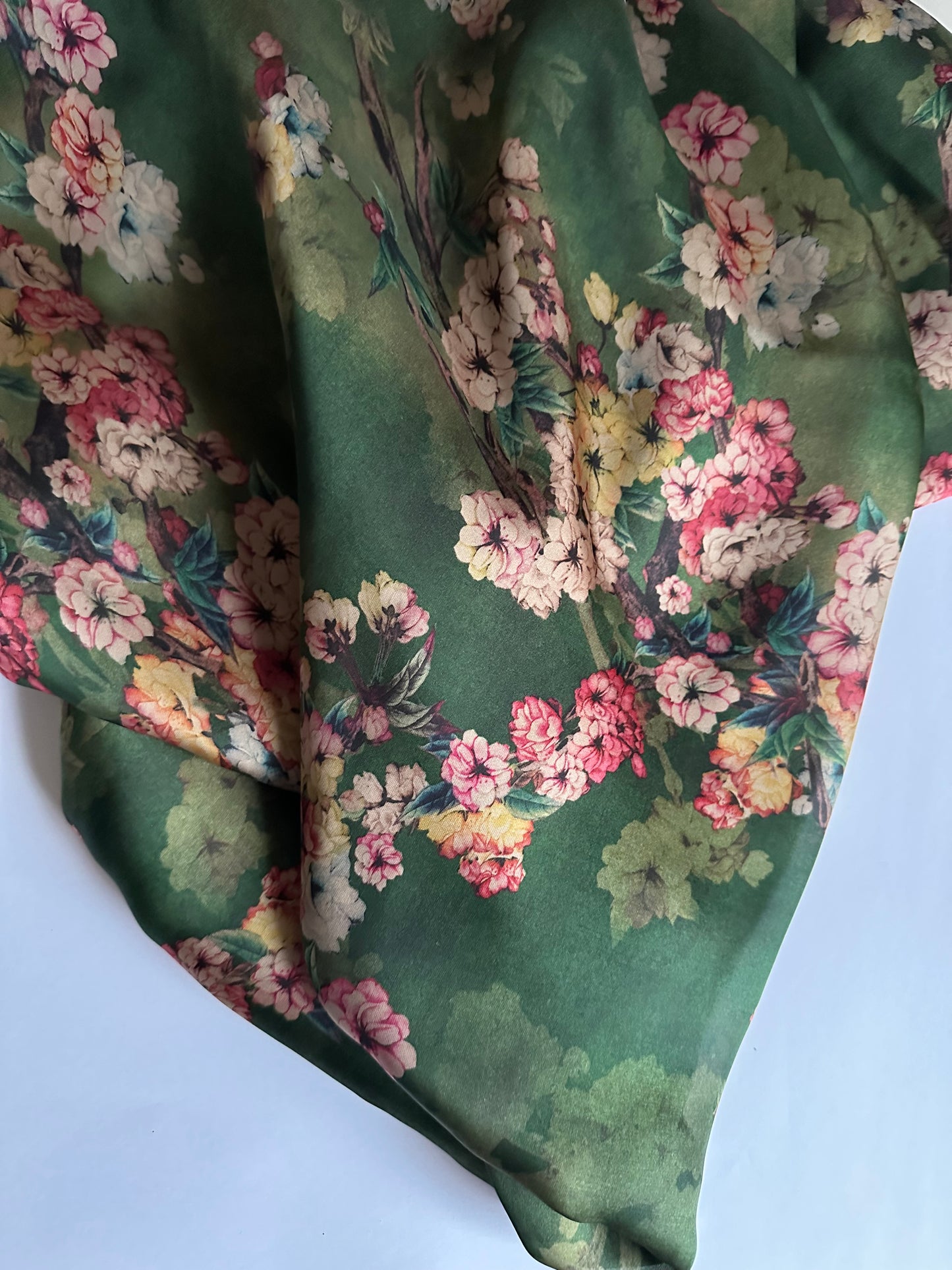 Luxury silk satin fabric in a green floral design for premium-quality dressmaking.