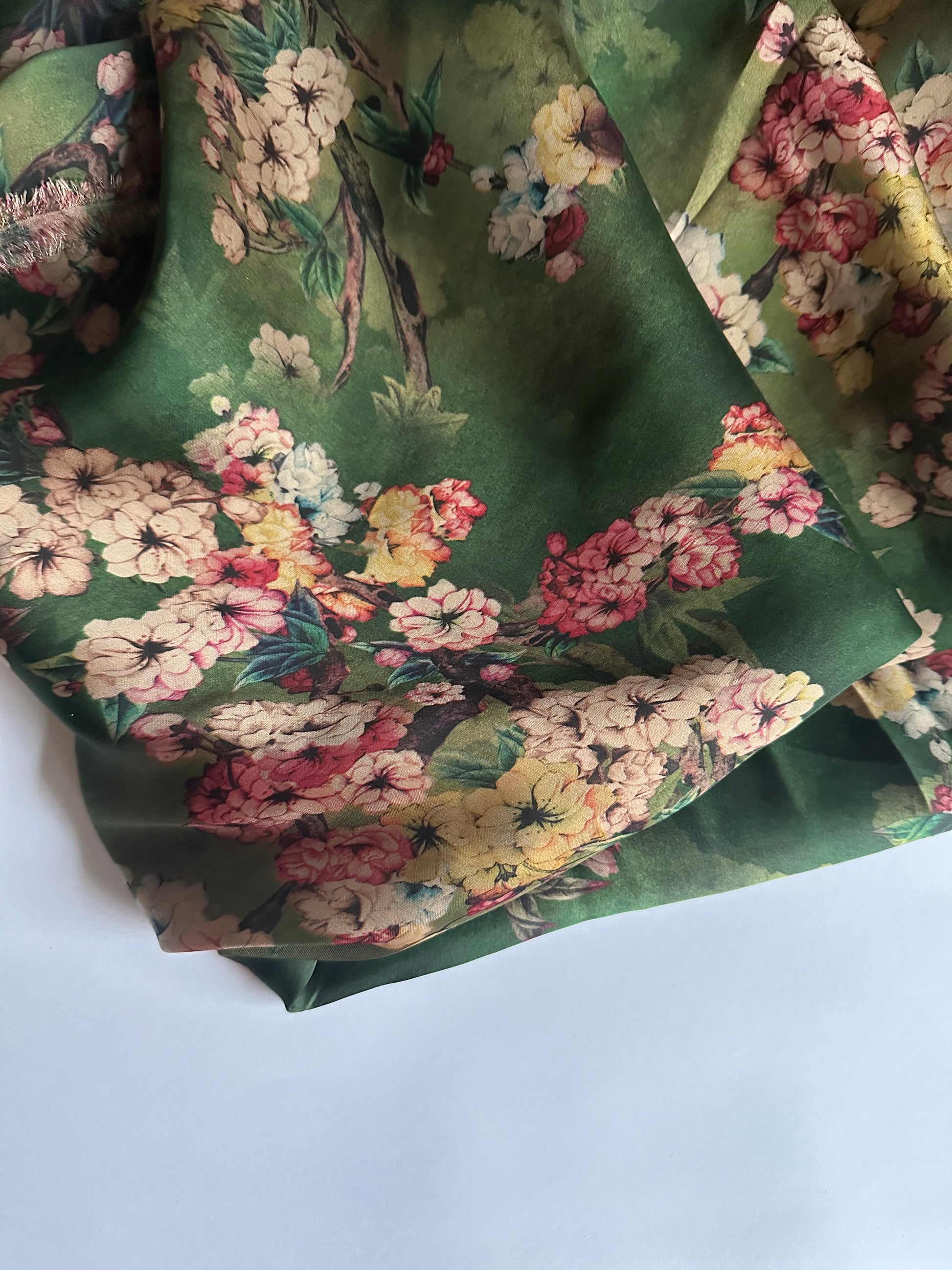 Soft and glossy green floral silk satin fabric for creating elegant and stylish dresses